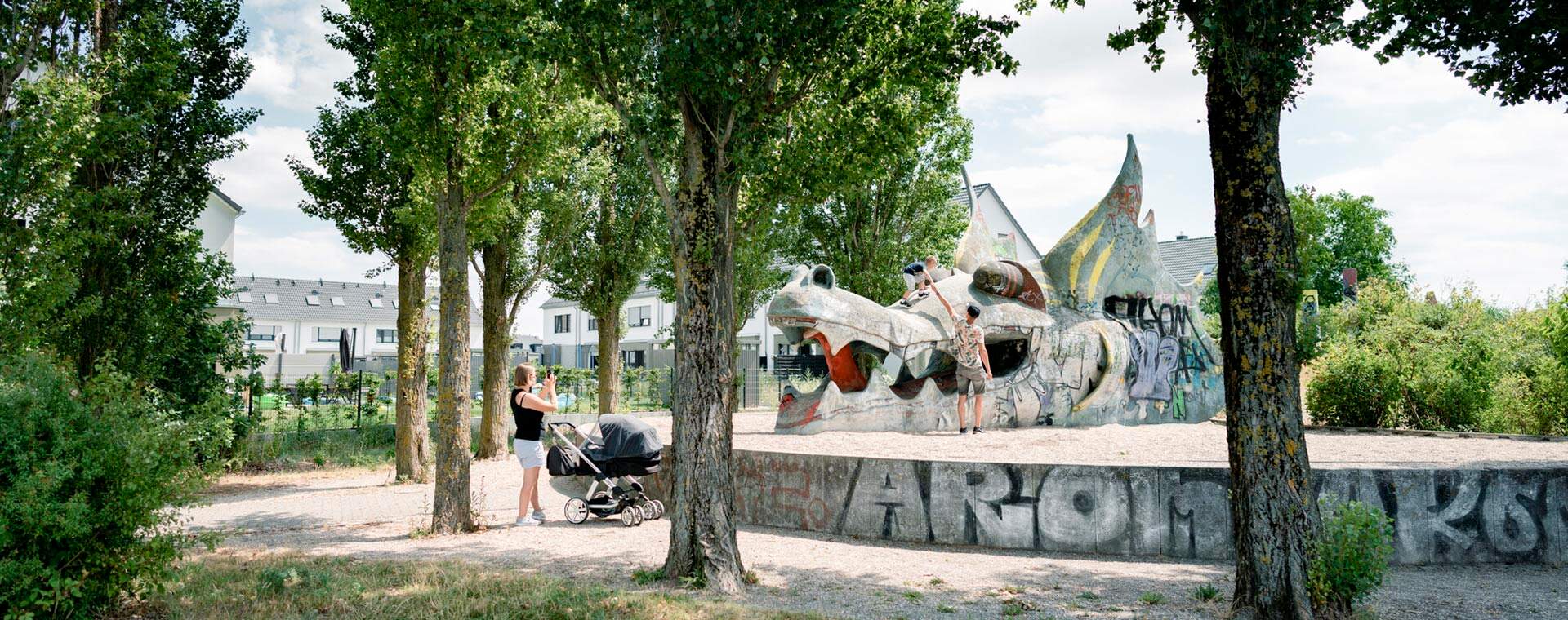 Großer Drachenspielplatz als Freizeittreffpunkt gleich nebenan Ein Park mit Bäumen, Spielplatz und buntem Drachen. Ideal für Familienausflüge.