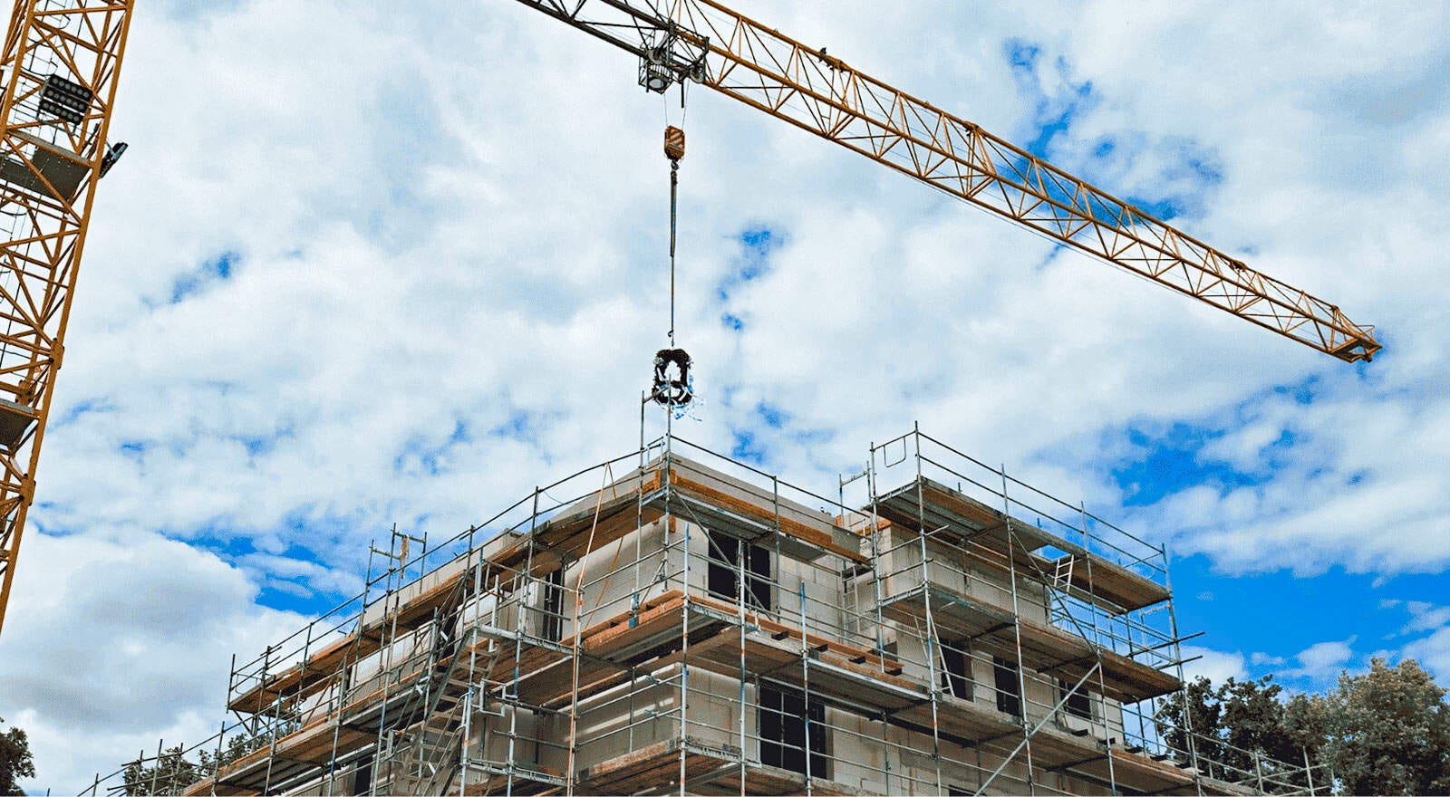 Der Kran lässt den Richtkranz über den Neubau schweben